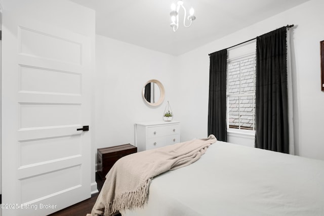 bedroom with dark wood-type flooring, multiple windows, and an inviting chandelier