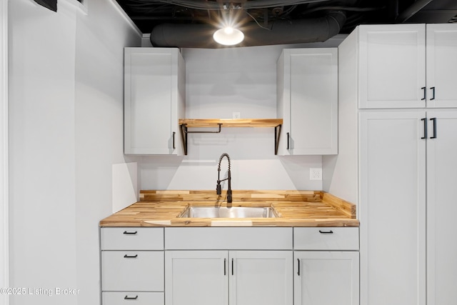 kitchen with white cabinets, open shelves, wooden counters, and a sink