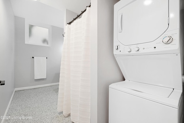 clothes washing area with baseboards, laundry area, and stacked washer / drying machine