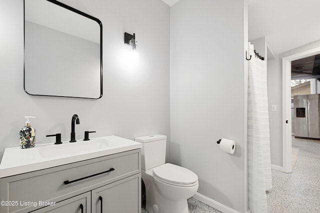 bathroom featuring baseboards, vanity, toilet, and speckled floor