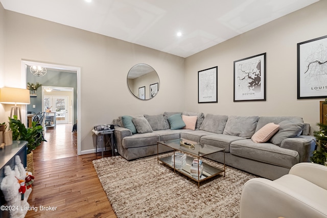 living area featuring light wood-type flooring, an inviting chandelier, and baseboards