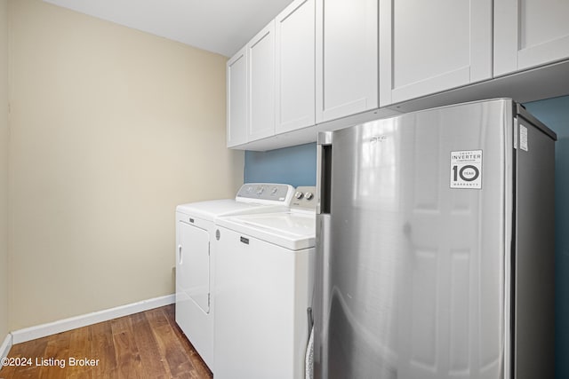 laundry area featuring washer and clothes dryer, wood finished floors, cabinet space, and baseboards