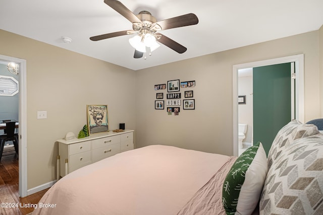 bedroom featuring a ceiling fan, ensuite bathroom, baseboards, and wood finished floors