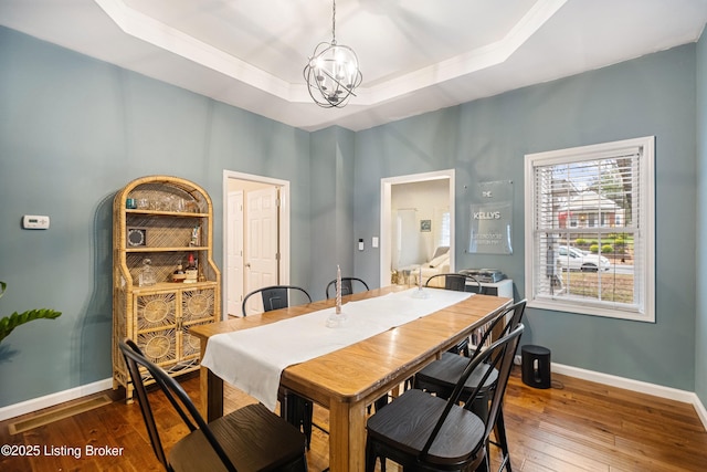 dining room with a tray ceiling, baseboards, a notable chandelier, and hardwood / wood-style floors