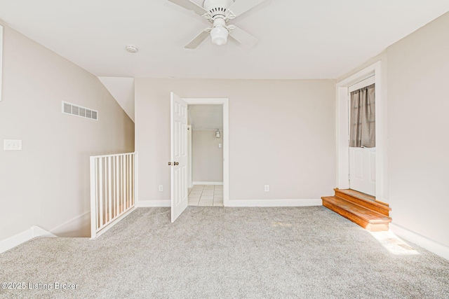 carpeted spare room featuring ceiling fan, visible vents, and baseboards