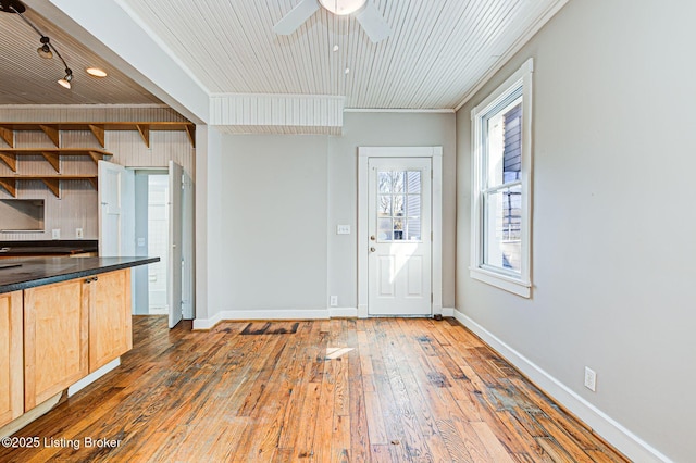 kitchen featuring dark countertops, wood-type flooring, light brown cabinetry, a ceiling fan, and baseboards