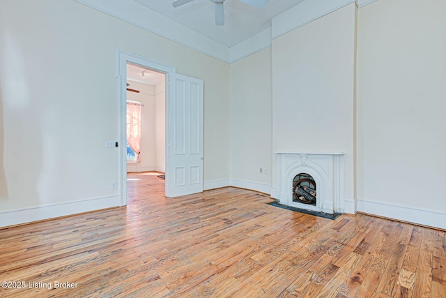 unfurnished living room featuring baseboards, a fireplace with flush hearth, hardwood / wood-style flooring, and a ceiling fan