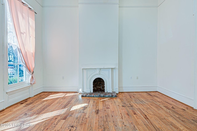 unfurnished living room featuring baseboards, a fireplace, and hardwood / wood-style floors