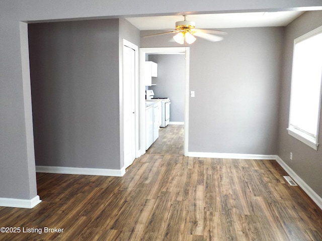 unfurnished room featuring a healthy amount of sunlight, baseboards, visible vents, and dark wood-type flooring