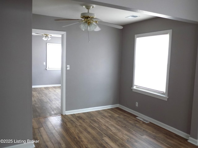 spare room featuring dark wood-style floors, visible vents, ceiling fan, and baseboards