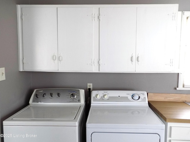 washroom featuring cabinet space and washer and clothes dryer