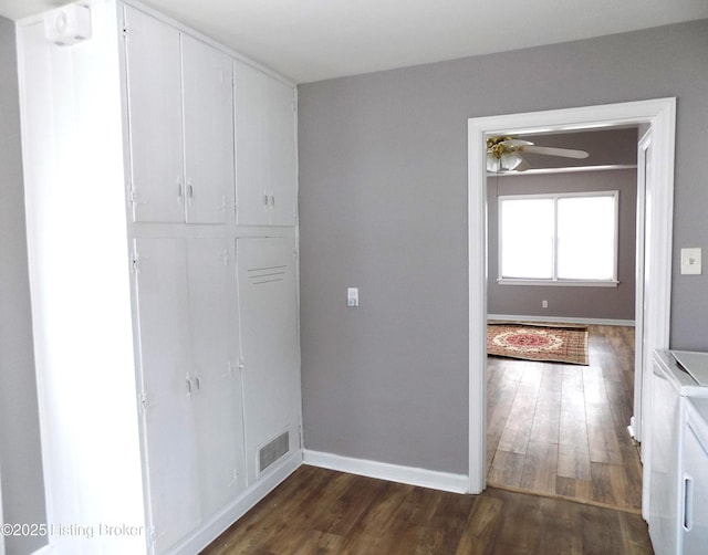 interior space with dark wood-style floors, washer and clothes dryer, visible vents, and baseboards