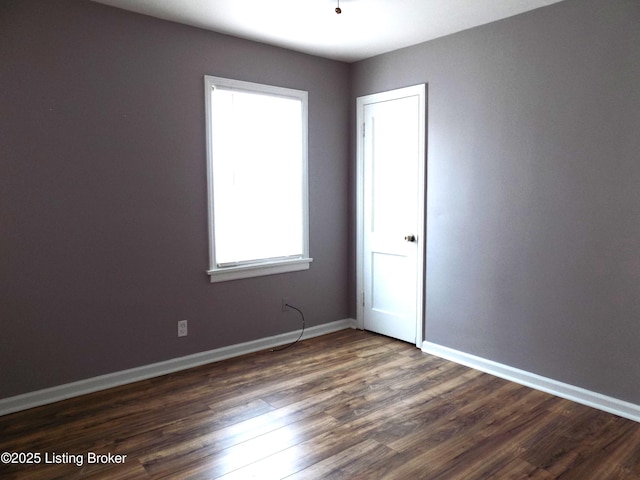 empty room featuring dark wood-style floors and baseboards