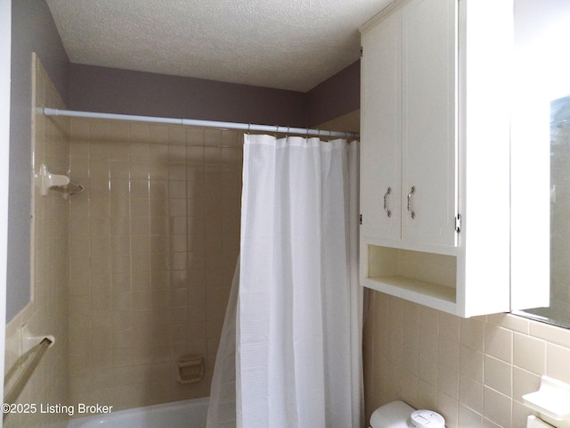 bathroom with shower / tub combo with curtain and a textured ceiling