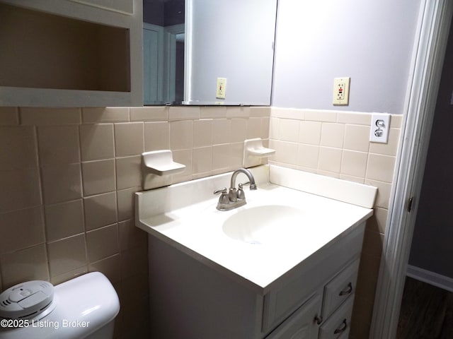 half bath with toilet, vanity, and tile walls