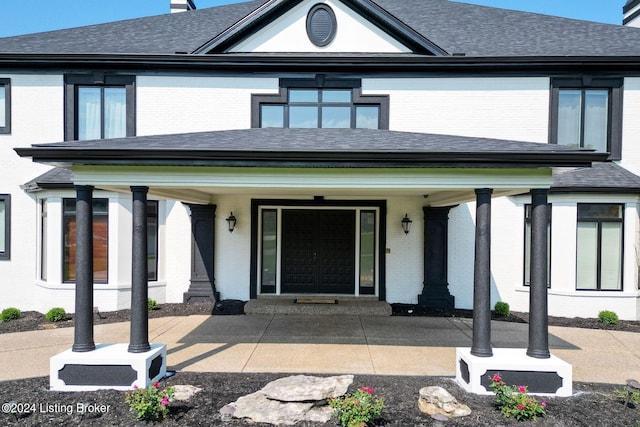 view of front of home featuring brick siding, a porch, and a shingled roof