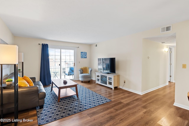 living room featuring visible vents, baseboards, and wood finished floors