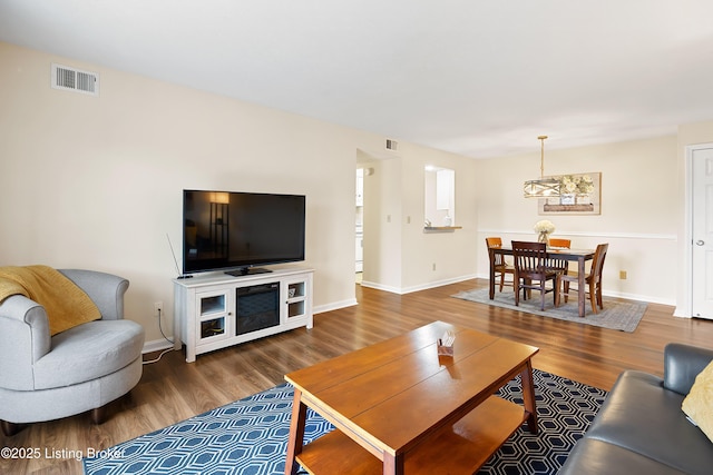 living area with wood finished floors, visible vents, and baseboards