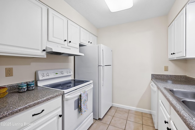 kitchen featuring white appliances, white cabinets, dark countertops, under cabinet range hood, and a sink