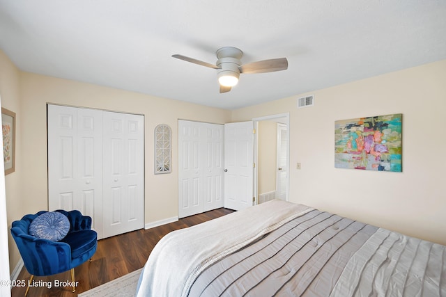 bedroom with dark wood-style floors, baseboards, visible vents, and two closets