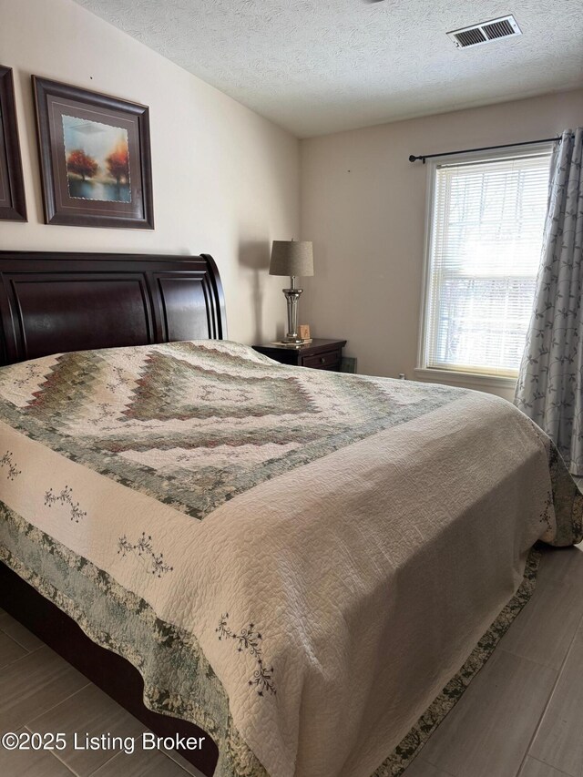 bedroom featuring a textured ceiling, wood finished floors, and visible vents