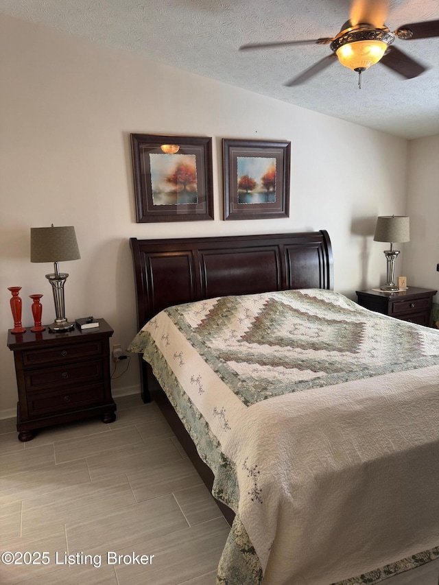 bedroom featuring lofted ceiling, ceiling fan, a textured ceiling, and baseboards