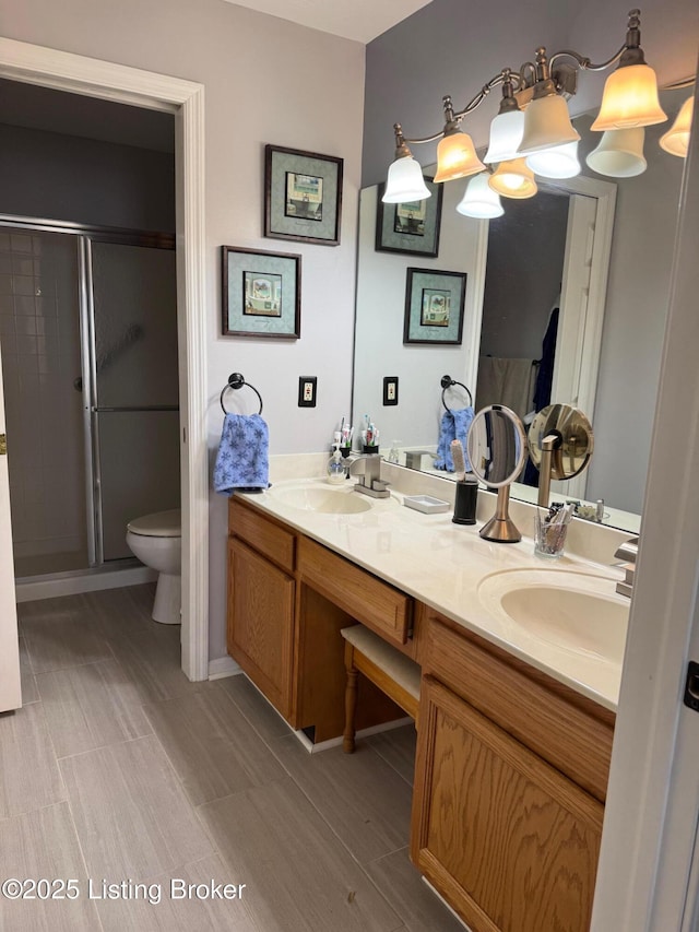full bathroom with double vanity, a sink, toilet, and a shower stall