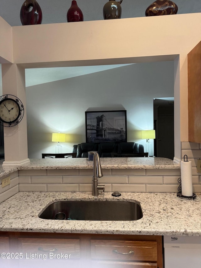 kitchen featuring a sink, dishwasher, and light stone countertops