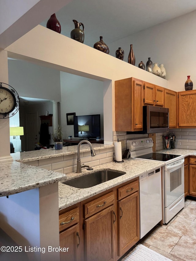 kitchen with brown cabinets, white appliances, a sink, and decorative backsplash