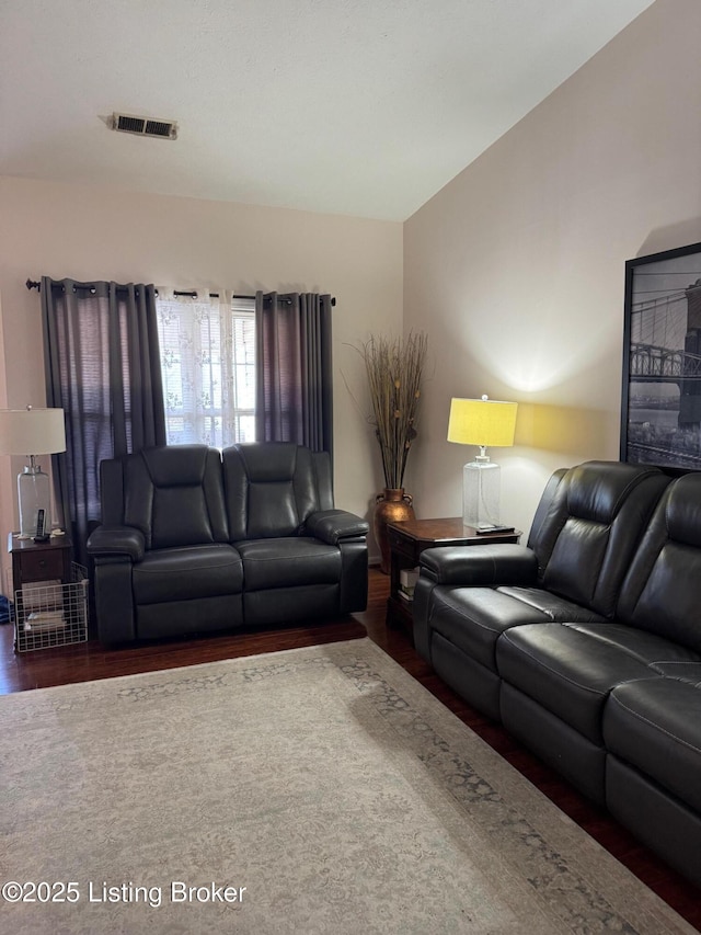 living room with visible vents, vaulted ceiling, and wood finished floors