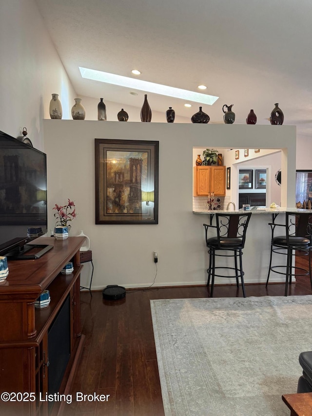 living room featuring vaulted ceiling with skylight, dark wood-style flooring, and recessed lighting