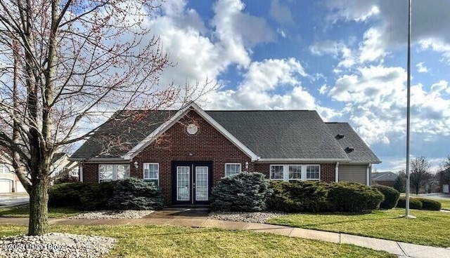 view of front of property featuring brick siding, a front lawn, and french doors