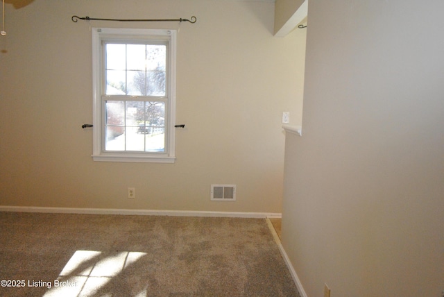 carpeted spare room with baseboards, visible vents, and a wealth of natural light