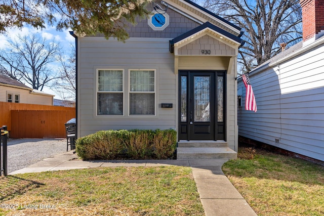 view of exterior entry featuring fence and a yard