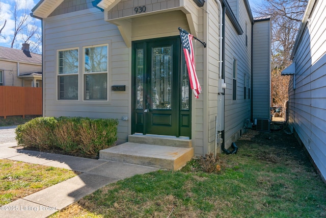 view of exterior entry with fence and central AC unit