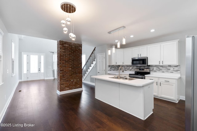 kitchen featuring stainless steel appliances, a sink, light countertops, tasteful backsplash, and dark wood finished floors