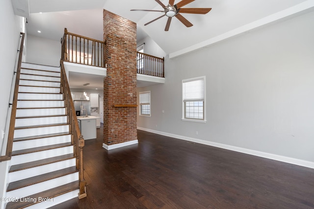 unfurnished living room with baseboards, ceiling fan, stairway, dark wood-type flooring, and high vaulted ceiling