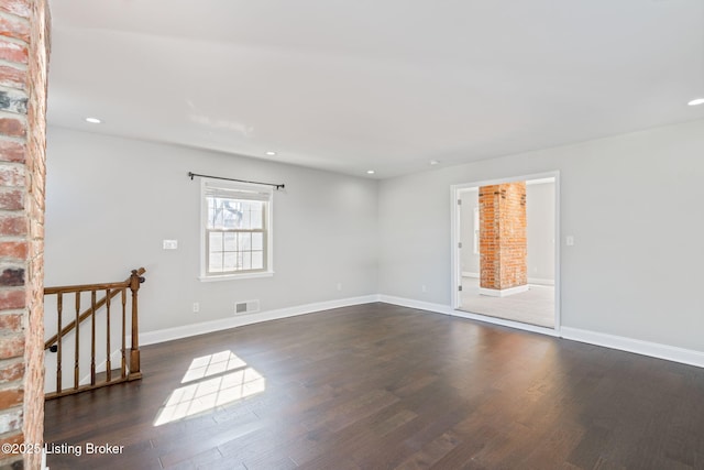 empty room featuring recessed lighting, dark wood-style flooring, visible vents, and baseboards