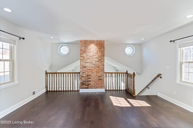 spare room with baseboards, wood finished floors, visible vents, and a healthy amount of sunlight