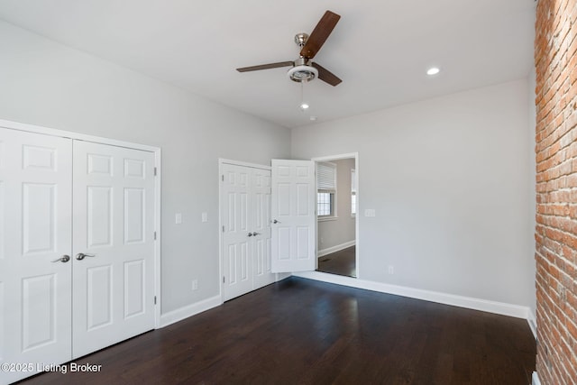 unfurnished bedroom featuring recessed lighting, a ceiling fan, dark wood finished floors, baseboards, and two closets