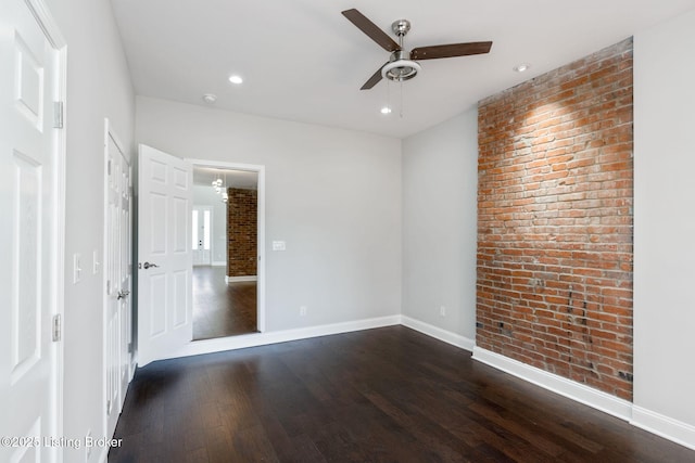 empty room with recessed lighting, brick wall, a ceiling fan, baseboards, and dark wood finished floors