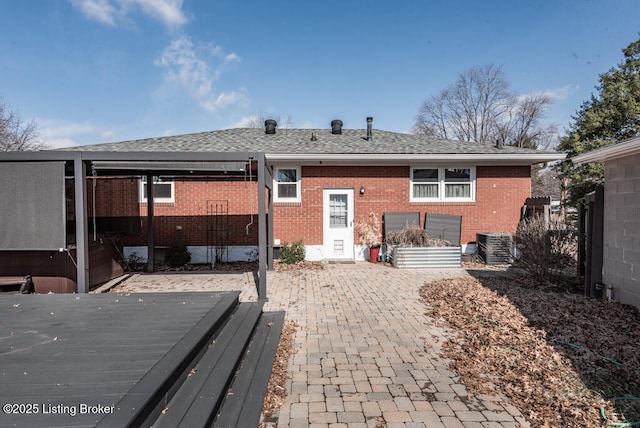 back of property featuring brick siding, a patio, roof with shingles, cooling unit, and a wooden deck