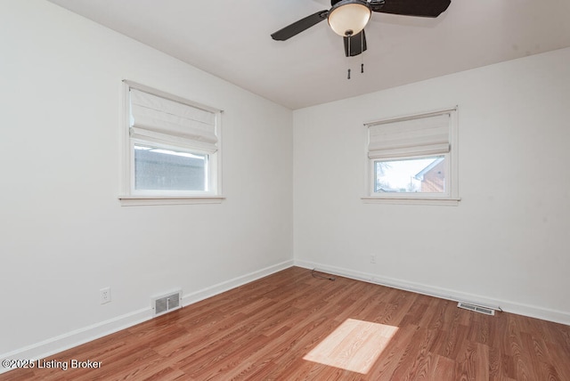 unfurnished room featuring light wood-style flooring, a ceiling fan, visible vents, and baseboards