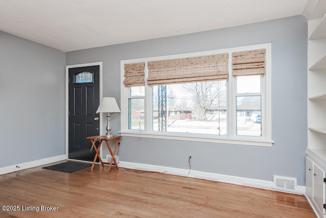 foyer featuring a wealth of natural light, light wood-style flooring, visible vents, and baseboards