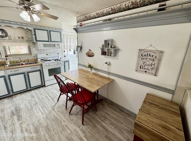 kitchen featuring light wood-style floors, white appliances, a sink, and a textured ceiling