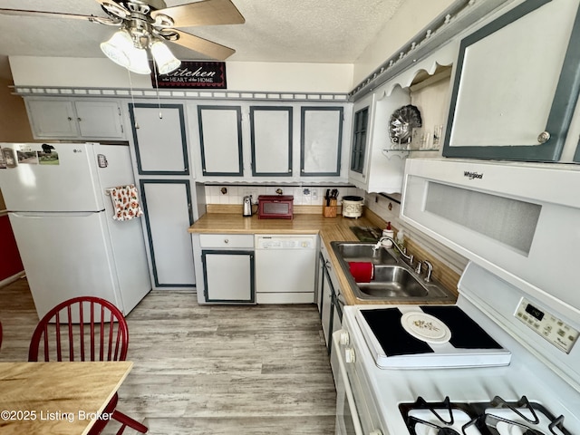 kitchen featuring light wood finished floors, a sink, a textured ceiling, ceiling fan, and white appliances