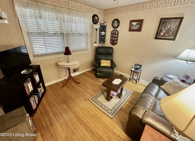 living room with wood-type flooring, visible vents, and baseboards