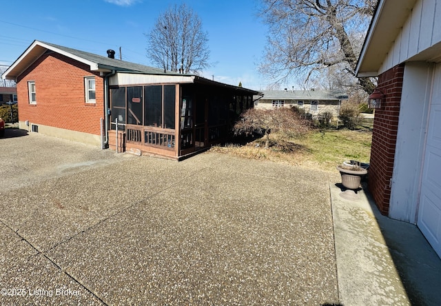 rear view of house featuring a sunroom and brick siding