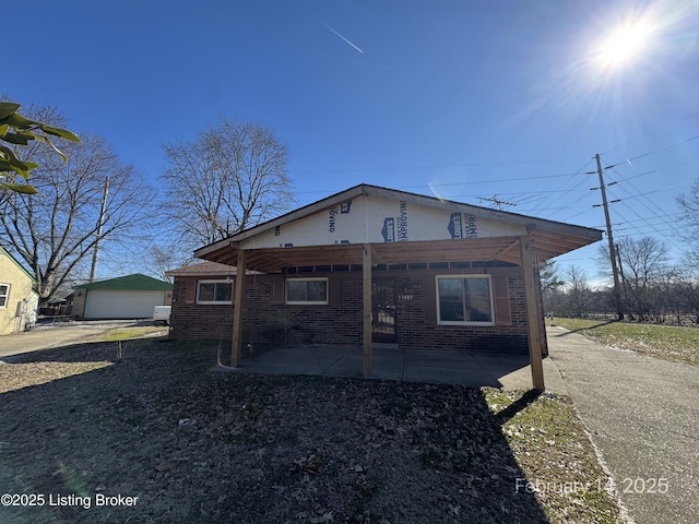 view of front of house with an outbuilding, brick siding, and a patio