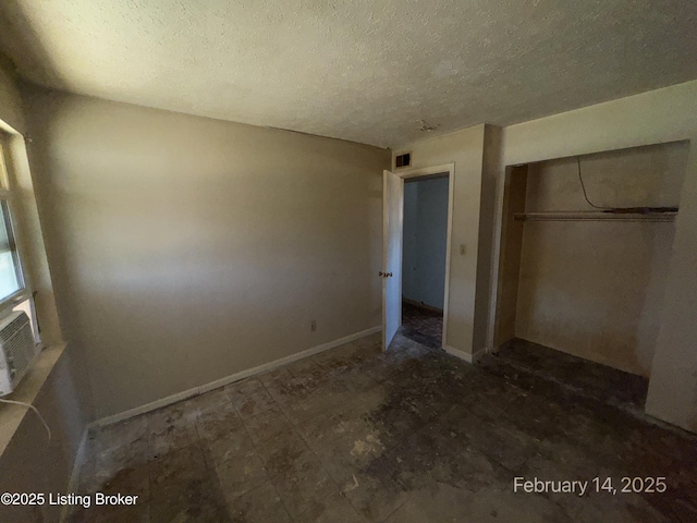 unfurnished bedroom featuring a textured ceiling, a closet, visible vents, and baseboards